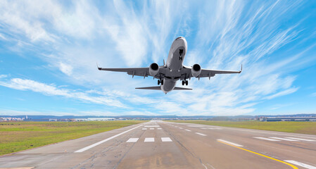 Fototapeta premium White Passenger plane fly up over take-off runway from airport 