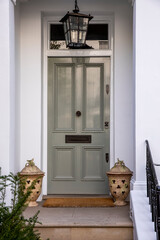 Front door of a house with some decorations and a black railing.