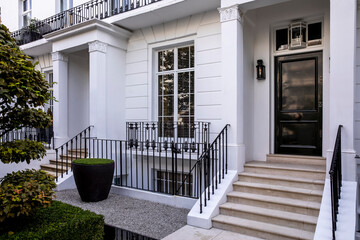 Entrance to a townhouse with matching black front doors. exterior is white.