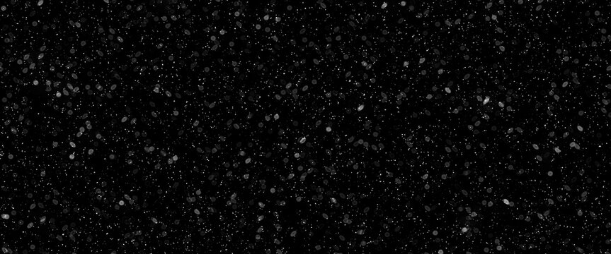 Snowfall bokeh on black background. Many snowflakes in flying in the air. Winte night snowfall and blizzard of snow at. Blur bokeh light effect creative background