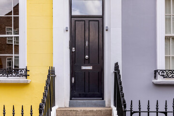 secured front door entrance, black front door with yellow and gray walls.