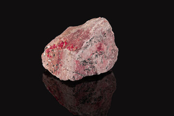 A raw shard of the mineral vanadinite. Pinkish stone with white and black patches