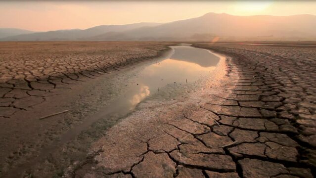 Landscape of river drying with dry cracked earth at sunset metaphor climate change, Global warming and Drought on summer, Heat wave and hot temperature impact to water source.