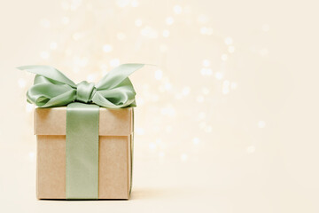 Gift box with green bow. christmas lights background, copy space. Winter holidays celebration concept.