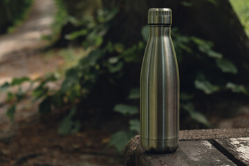 Water bottle. Reusable steel thermo water bottle on wooden bench. Sustainable lifestyle. Plastic...