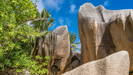 Picturesque granite rocks with bizarre outlines against a background of blue sky and clouds. Lush...