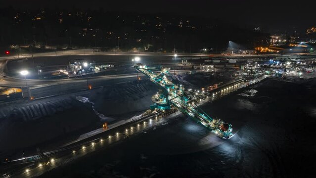 Rotary shovel at coal pile, bulk shipping terminal, aerial hyperlapse, silos, grain elevators, freight vessels, North Vancouver, BC. 4K 24FPS