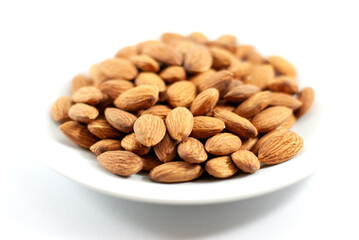 Tasty almond in white plate on white background, selective focus.