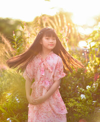 backlight Portrait of a beautiful Asian girl 9 years old with long hair spinning garden