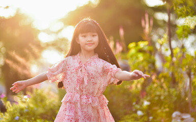 backlight Portrait of a beautiful Asian girl 9 years old with long hair spinning garden