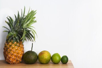 Pineapple and citrus fruits on a wooden table against white background