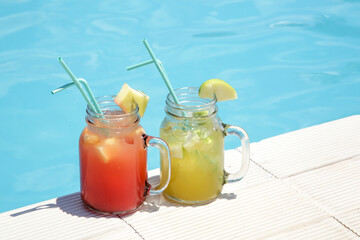 Colorful refreshing cocktails in glass jars next to the pool