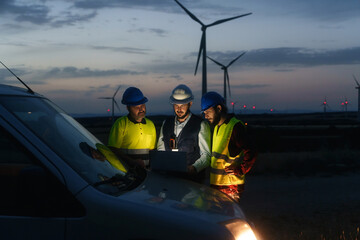 Technicians engineers working in wind turbine electricity plant at night. Renewable energy solution...