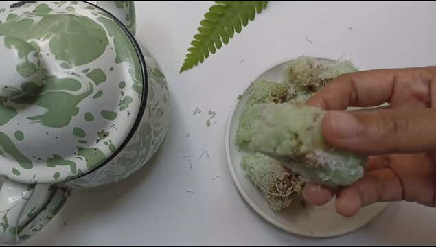Hand open kue putu bamboo or putu cake. Viewing the deliciousness of brown sugar inside the rice flour which sprinkled with grated coconut.