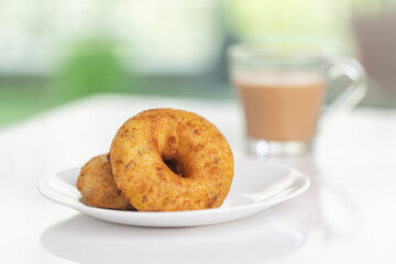 plate of methu vadai with cup of tea on table.