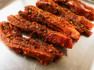 Pork belly slices marinated in orient style sous with herbs on a metal tray. Selective focus. Uncooked pork product for barbeque or frying with delicate special flavor.
