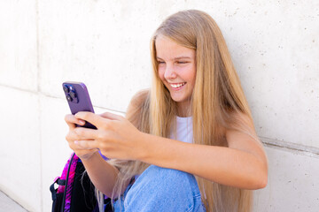 Smiling teenage girl using mobile phone outdoors