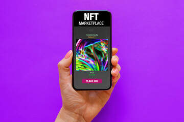 Mobile phone held in hand with sample NFT marketplace website on the screen