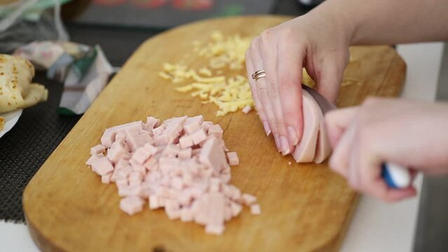 slicing ham in the kitchen on a wooden board for cooking a dish, close-up