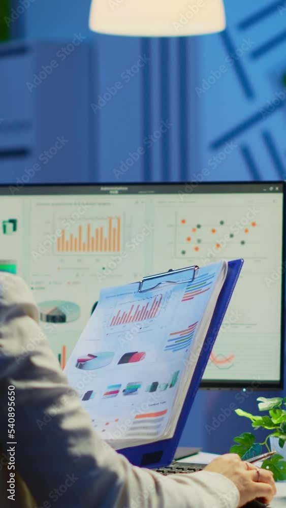 Poster vertical video: back view of manager analysing graphics and financial statistics from clipboard work