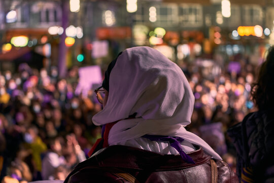 Portrait of an arab woman from the back facing a crowd at a feminist demonstration