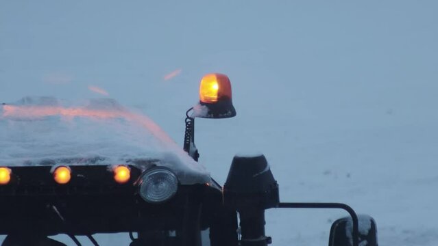 Orange flasher on the roof of a snowplow with snow storm in winter. Copy space for text, evening