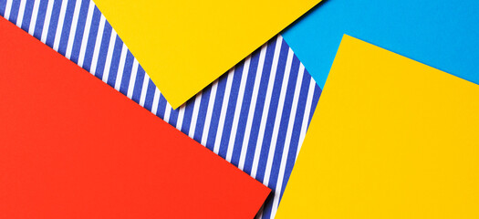 Abstract geometric fashion colored papers texture background. Yellow, red, blue and striped paper background. Top view, flat lay