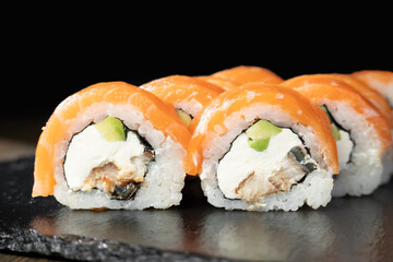 Sushi roll with salmon, smoked eel, avocado, cream cheese on black background. Sushi menu. Japanese food.