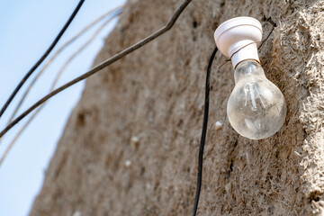 a bulb without electricity is hanging on a muddy wall in the village