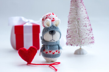 Knitted bunny with gifts on a wooden background with a Christmas tree. New Year of the hare 2023, handmade