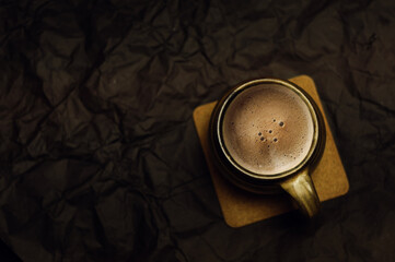 Ceramic mug with coffee on dark paper background