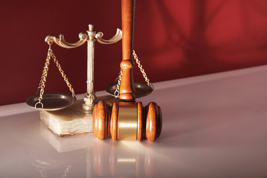 gavel hammer and libra scale against red background