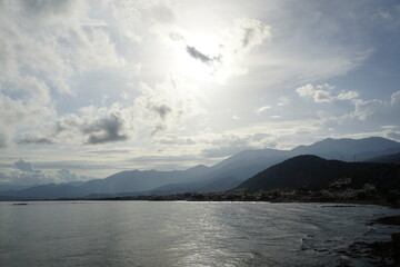 Sunrise over the mountains on the shores of the Aegean Sea. October morning. The magic of nature. The island of Crete. Bright light and haze perspective.