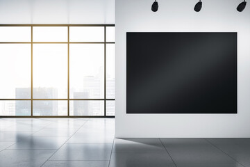 Big blank black illuminated billboard with space for your advertisement on light wall in sunlit empty hall with grey floor and city skyscrapers view from panoramic window. 3D rendering, mock up