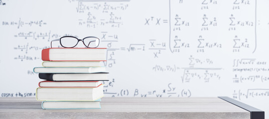 Close up of stacked books and glasses on white mathematical formulas background. School and...