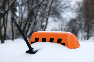 Roof of city taxi and orange symbol covered with snow. Snowfall, heavy precipitation and snow drifts paralyze traffic