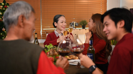 Happy family celebrating winter holidays together and drinking red wine at dining table. Holidays, celebration and people concept
