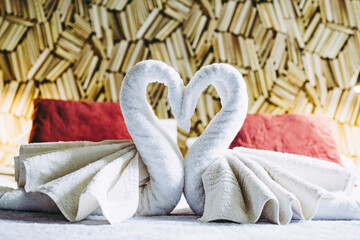 Serviettes en éponge pliées en forme de cygne sur le lit d'une chambre d'hôtel luxueuse
