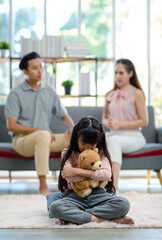 Asian unhappy sad depressed stressed little girl daughter sitting on carpet floor hugging holding...