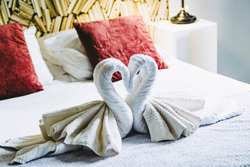 Serviettes en éponge pliées en forme de cygne sur le lit d'une chambre d'hôtel luxueuse