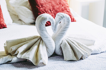 Serviettes en éponge pliées en forme de cygne sur le lit d'une chambre d'hôtel luxueuse