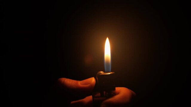 close-up fire from the lighter igniting in the hand in the dark on a dark room