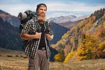 Smiling bearded hiker with a backpack on a mountain