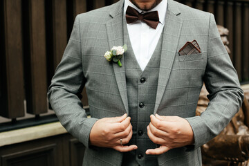 Elegant man in a suit whith boutonniere adjusts his jacket, business and wedding concept