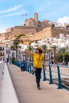 A young woman with a hat on vacation in spring in Ibiza town next to the lighthouse, Balearic Islands