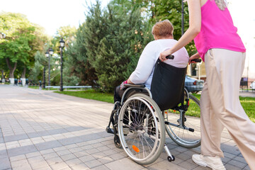 Young female caregiver pushing wheelchair with female person with disability across city street