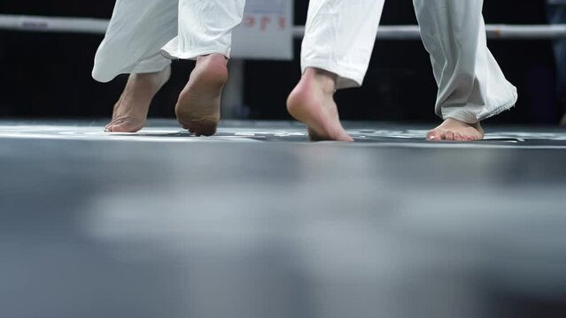 Legs of athletes who practice karate in the ring. Indoor sports event.