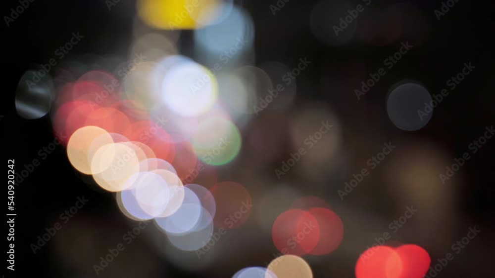 Poster beautiful glittering bokeh in dark blurry background at night. the round colorful bokeh shine from c