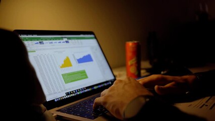 Student behind computer in dark room with excel sheet