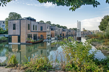 Rotterdam, The Netherlands, October 12, 2022: row of floating villas with wooden facades in an old harbour basin in Feijenoord neighbourhood
